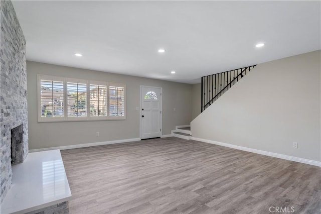 foyer with light wood-type flooring and a stone fireplace