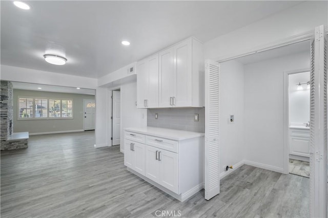 kitchen with white cabinets, backsplash, and light hardwood / wood-style flooring