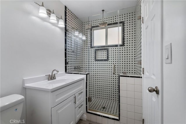 bathroom featuring vanity, toilet, and a shower with shower door