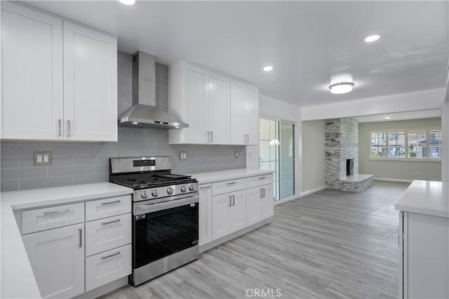 kitchen with gas range, white cabinetry, and wall chimney range hood