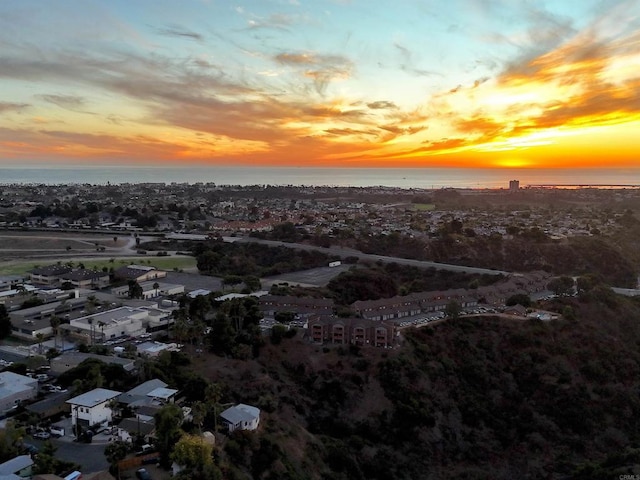 aerial view at dusk featuring a water view