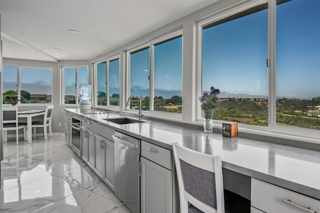 kitchen featuring light countertops, marble finish floor, appliances with stainless steel finishes, and a sink