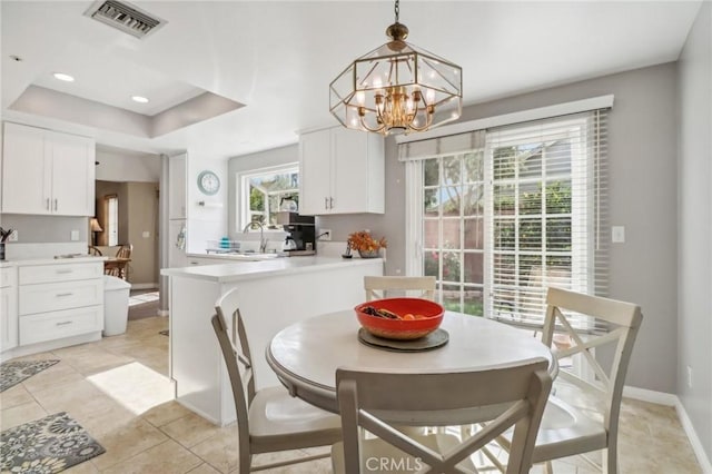 dining space featuring sink, light tile patterned floors, and an inviting chandelier