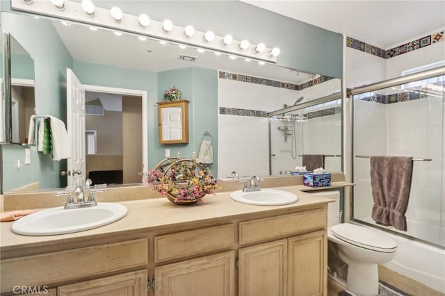 full bathroom featuring combined bath / shower with glass door, vanity, and toilet