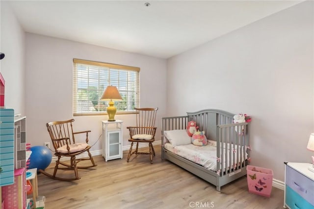 bedroom with light hardwood / wood-style floors and a crib