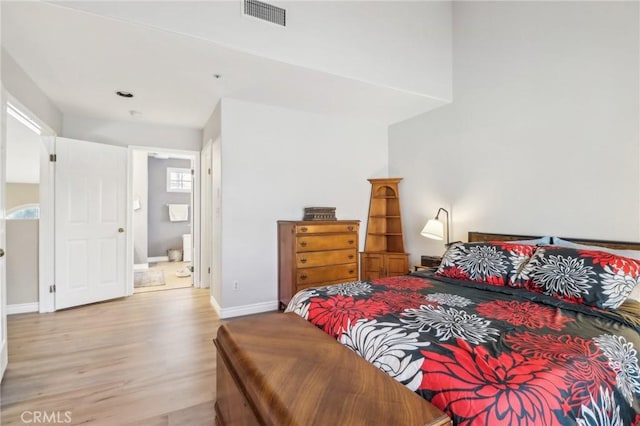 bedroom featuring connected bathroom and light hardwood / wood-style flooring