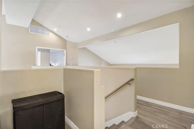 stairway featuring lofted ceiling and hardwood / wood-style flooring