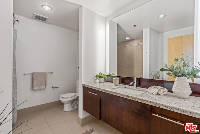 bathroom with toilet, a tile shower, vanity, and tile patterned floors