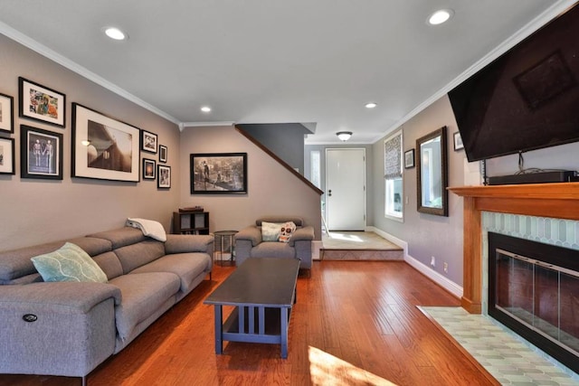 living room featuring hardwood / wood-style flooring, a tile fireplace, and crown molding