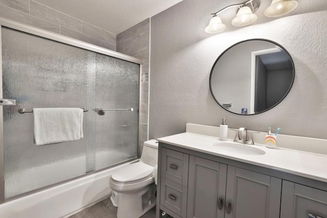 full bathroom featuring vanity, shower / bath combination with glass door, and toilet