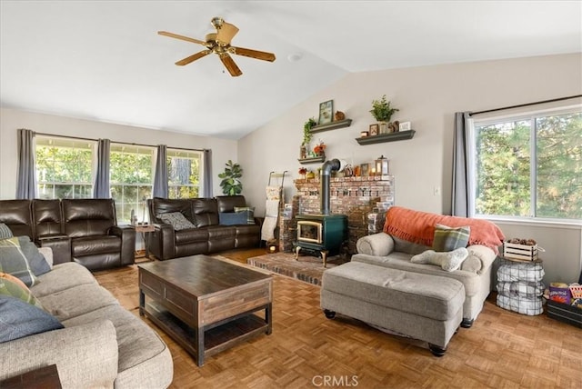 living room featuring light parquet floors, vaulted ceiling, a wood stove, and ceiling fan