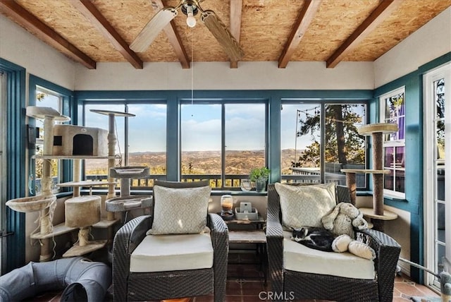 sunroom / solarium featuring beamed ceiling, a wealth of natural light, and ceiling fan