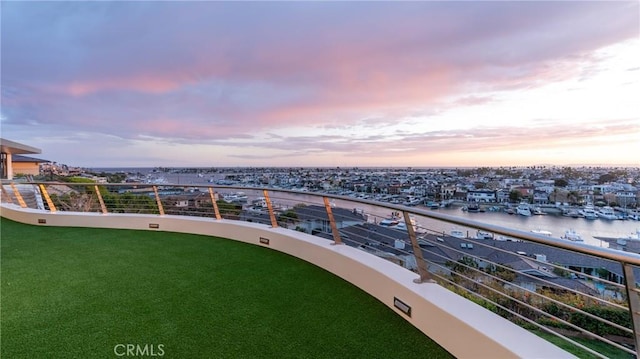 balcony at dusk featuring a water view