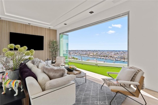 interior space with hardwood / wood-style floors, a water view, and a tray ceiling