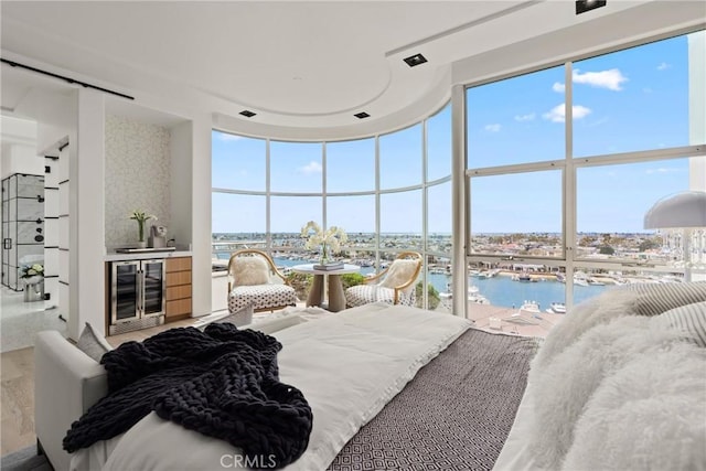 bedroom with multiple windows, a water view, beverage cooler, and hardwood / wood-style flooring