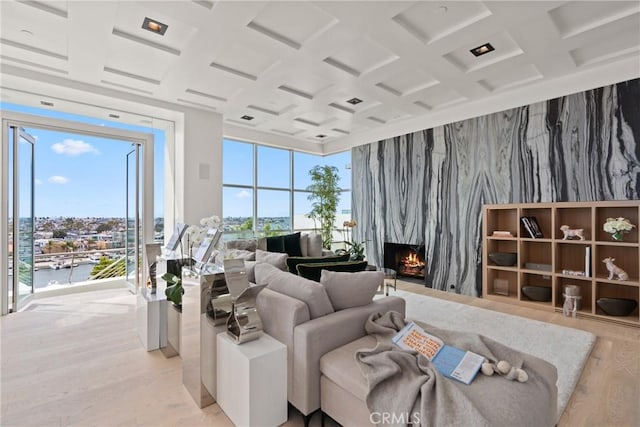 living room featuring a premium fireplace, a water view, light hardwood / wood-style floors, and coffered ceiling