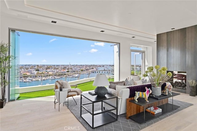 living room featuring a wealth of natural light, hardwood / wood-style floors, a water view, and golf simulator