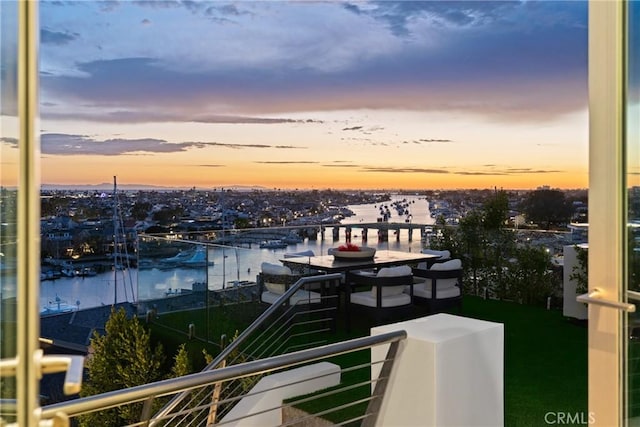 balcony at dusk featuring a water view