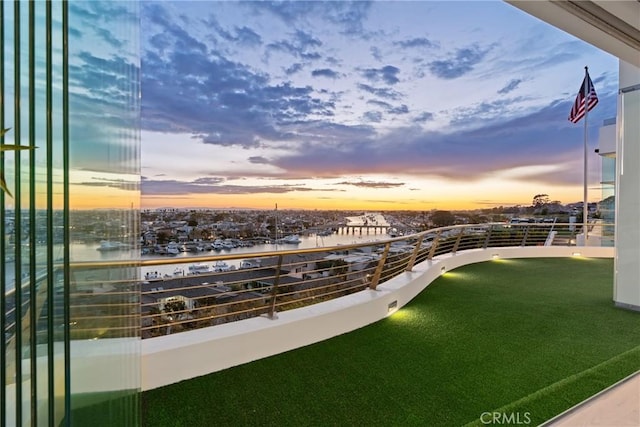 balcony at dusk featuring a water view