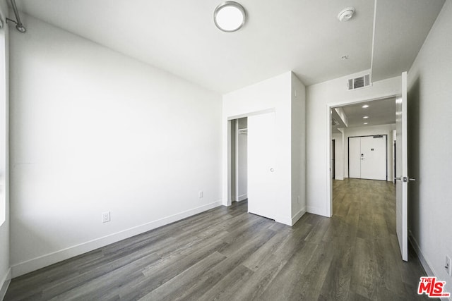 unfurnished bedroom with dark hardwood / wood-style floors and a closet