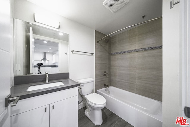 full bathroom featuring vanity, wood-type flooring, tiled shower / bath combo, and toilet