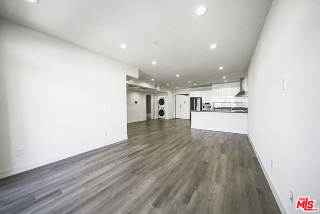 unfurnished living room featuring stacked washer / dryer and dark hardwood / wood-style floors