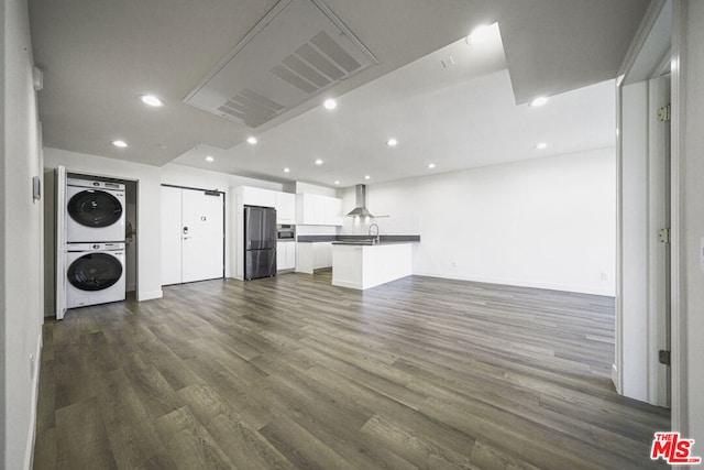 unfurnished living room with stacked washer / drying machine, sink, and dark wood-type flooring