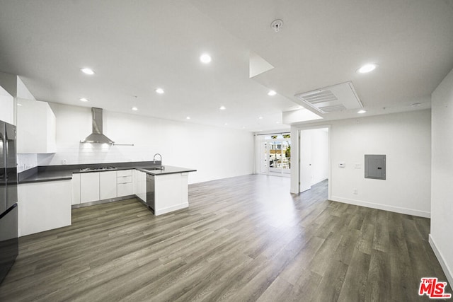 kitchen featuring kitchen peninsula, dark hardwood / wood-style flooring, sink, wall chimney range hood, and white cabinetry