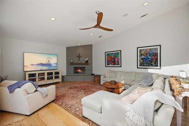 living room featuring a tile fireplace, ceiling fan, and light hardwood / wood-style floors