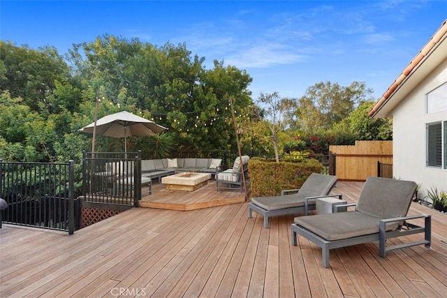 wooden terrace featuring an outdoor living space with a fire pit