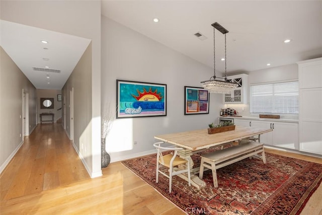 dining room with vaulted ceiling and light hardwood / wood-style flooring