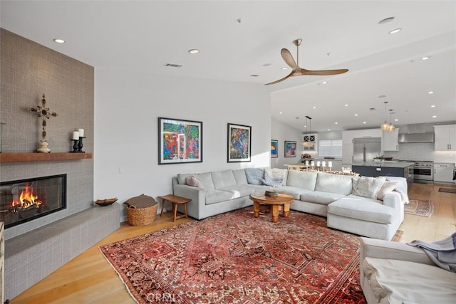 living room featuring ceiling fan, light hardwood / wood-style floors, and a fireplace