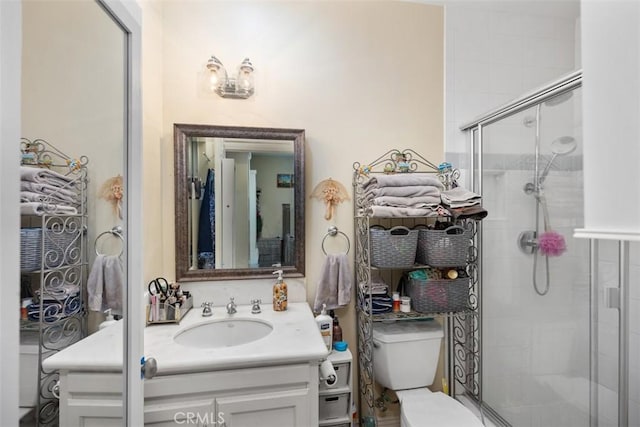 bathroom featuring vanity, toilet, and a shower with door