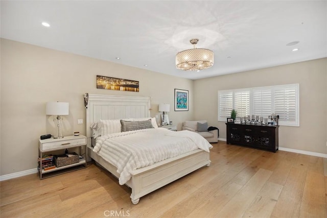 bedroom with light hardwood / wood-style floors and an inviting chandelier