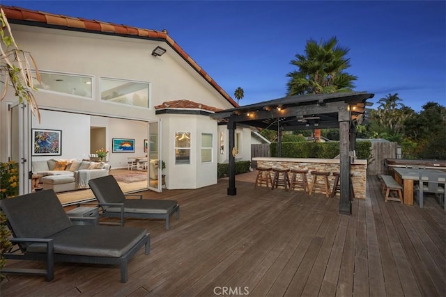 deck at dusk with an outdoor hangout area and a bar