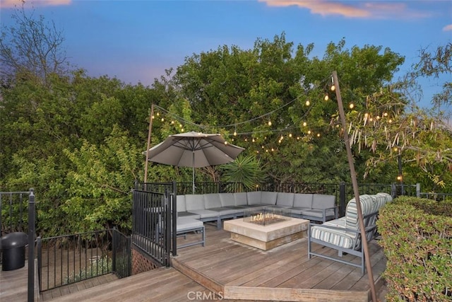 deck at dusk with an outdoor living space with a fire pit