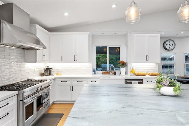 kitchen with vaulted ceiling, white cabinetry, wall chimney exhaust hood, and range with two ovens