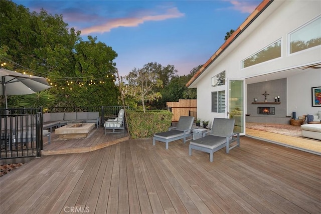 deck at dusk with an outdoor living space with a fireplace