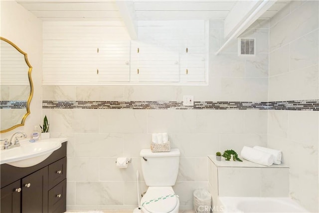 bathroom featuring toilet, vanity, and a tub to relax in