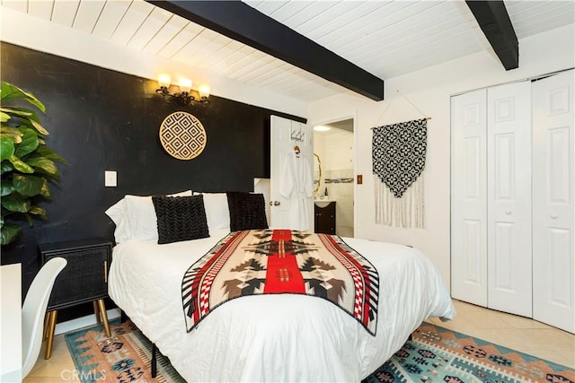 bedroom with a closet, light tile patterned floors, and beamed ceiling