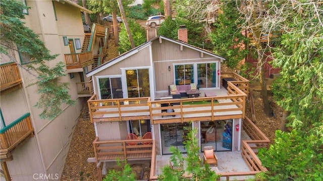 rear view of house with a wooden deck and a patio