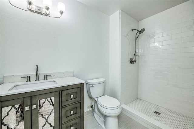 bathroom with a tile shower, vanity, toilet, and tile patterned floors