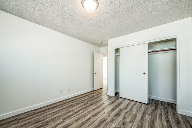 unfurnished bedroom featuring dark hardwood / wood-style flooring, a textured ceiling, and a closet