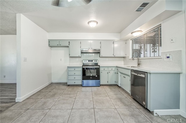 981 N Thorne Ave, Fresno, CA 93728 - kitchen featuring appliances with stainless steel finishes, under cabinet range hood, light countertops, light tile patterned flooring, and a textured ceiling