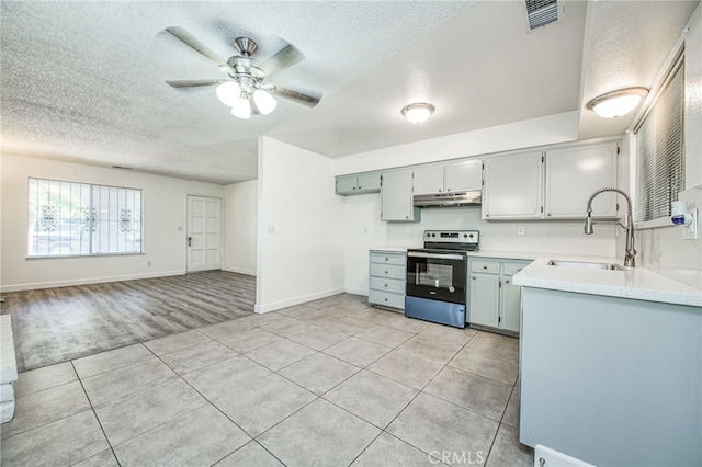 981 N Thorne Ave, Fresno, CA 93728 - kitchen with stainless steel electric stove, under cabinet range hood, light tile patterned flooring, a textured ceiling, and ceiling fan