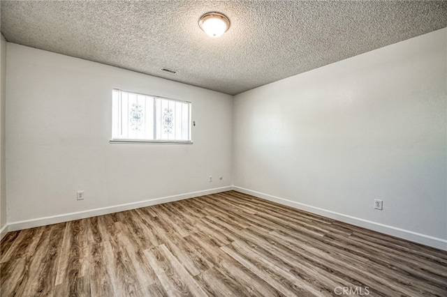 unfurnished room with hardwood / wood-style floors and a textured ceiling