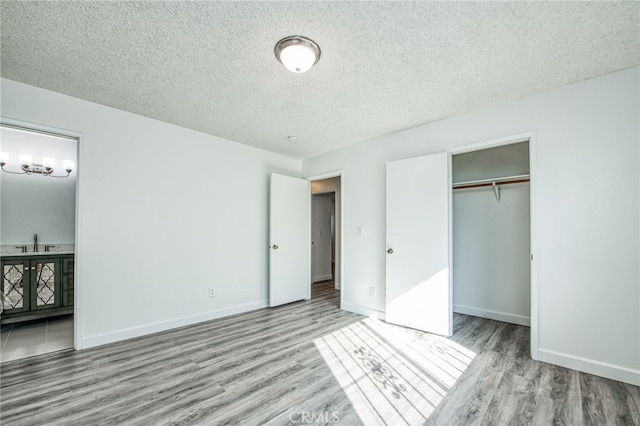 unfurnished bedroom with a textured ceiling, light wood-type flooring, a closet, and sink