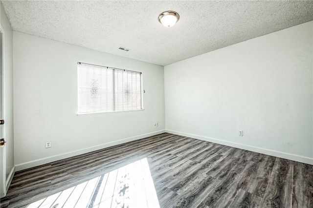 empty room featuring a textured ceiling and dark wood-type flooring