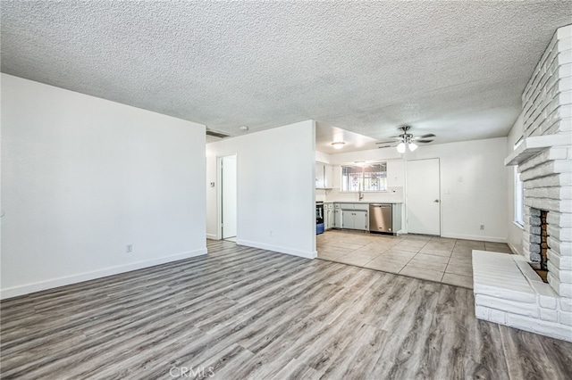 981 N Thorne Ave, Fresno, CA 93728 - unfurnished living room featuring light wood finished floors, ceiling fan, a brick fireplace, and a textured ceiling