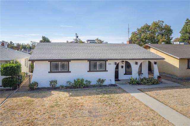 ranch-style home featuring covered porch and a front lawn